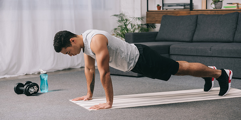 Man doing push ups in sportswear on fitness mat